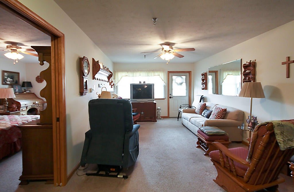 A cozy living room with a sofa, TV, and ceiling fan.