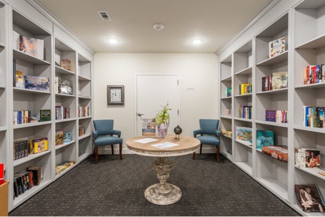 A cozy library corner with bookshelves, a round table, and two chairs.