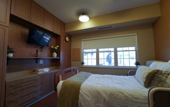 A neatly arranged hospital room with a bed and television.