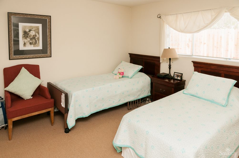 A tidy bedroom with two twin beds, a nightstand, and a lamp.