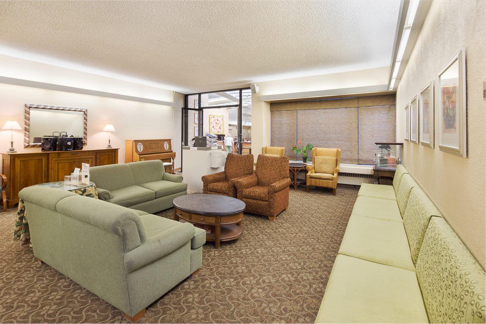 A spacious living room with multiple sofas, chairs, and a coffee table arranged on a carpeted floor.