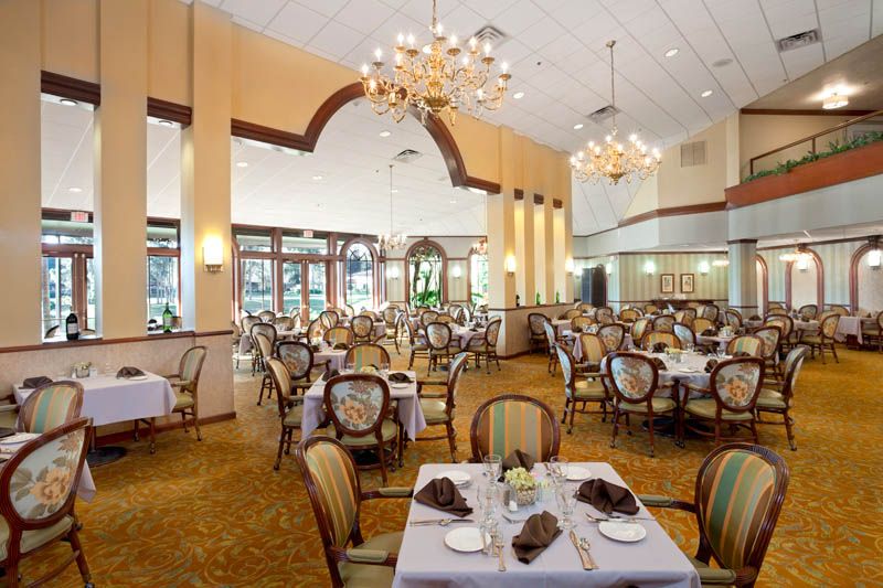 An elegant restaurant dining area with neatly arranged tables and chairs, illuminated by chandeliers.