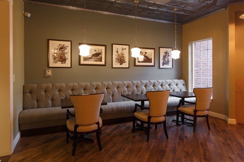 A cozy restaurant interior featuring booth seating, comfortable chairs, and decorated walls with framed art.