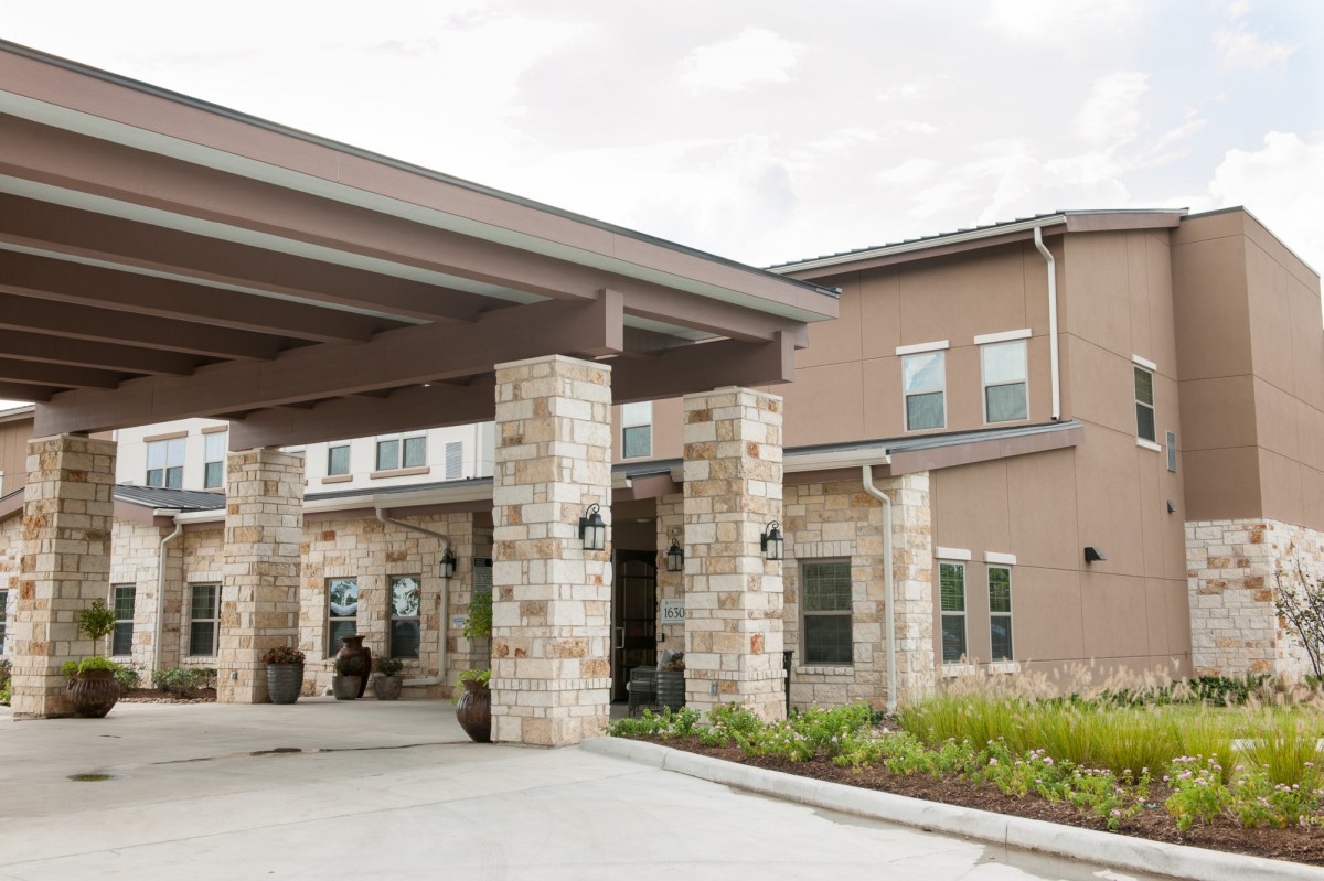 A modern building entrance with stone columns and landscaping.