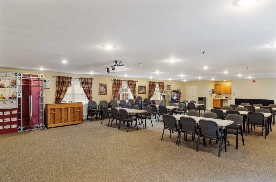 A spacious conference room set up with tables and chairs, equipped with a projector for presentations.