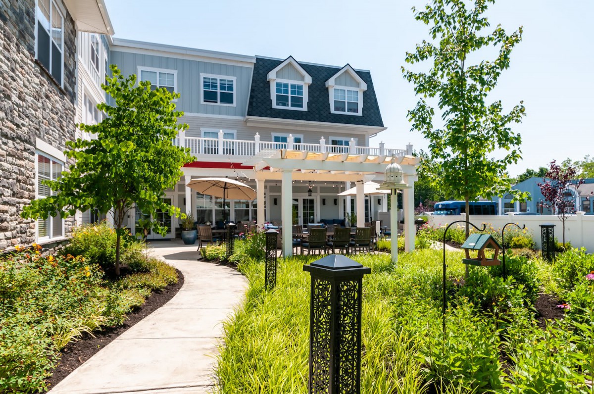 A beautifully landscaped garden path leading to a charming building with outdoor seating.
