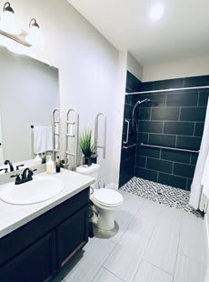 A modern bathroom featuring a sleek sink area, toilet, and spacious shower.