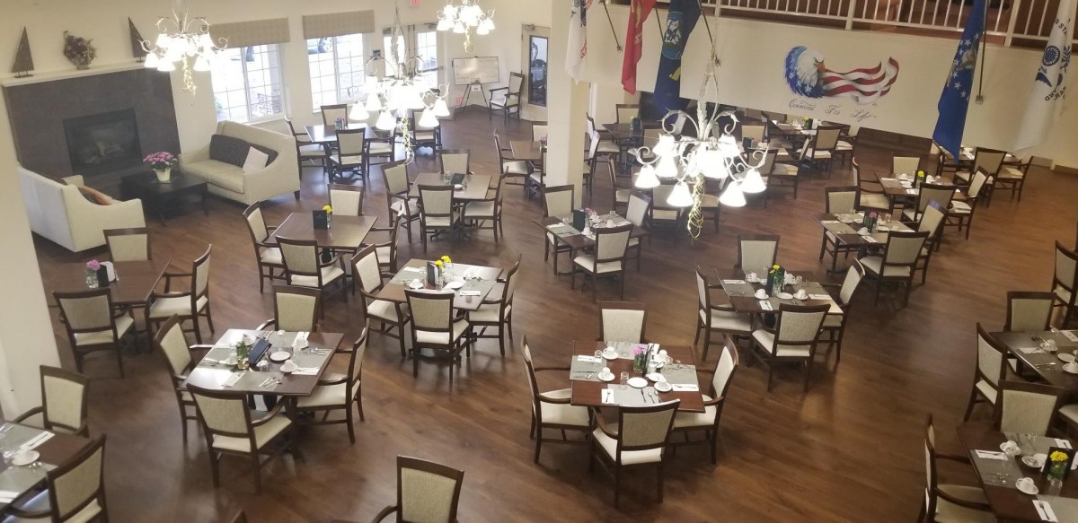 A spacious dining area with multiple round tables and elegant lighting fixtures.