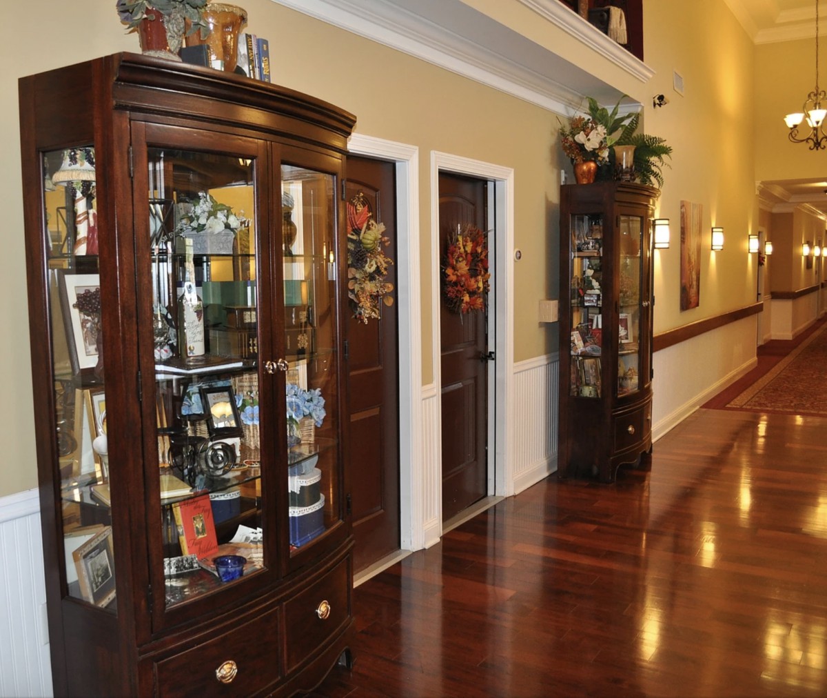 A hallway with polished wooden floors, featuring elegant display cabinets filled with various decorative items.