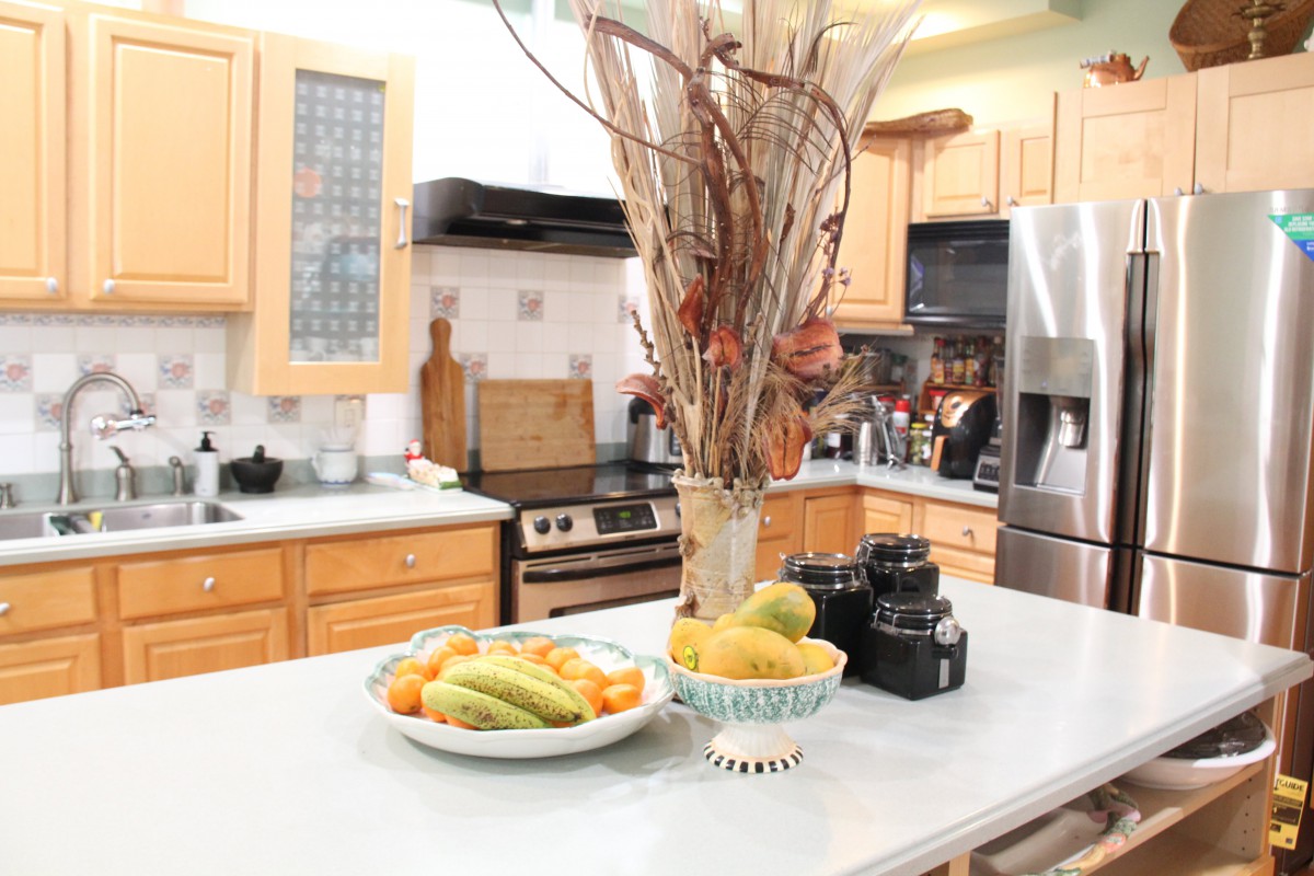 A modern kitchen with fruit and decorative items on the countertop.