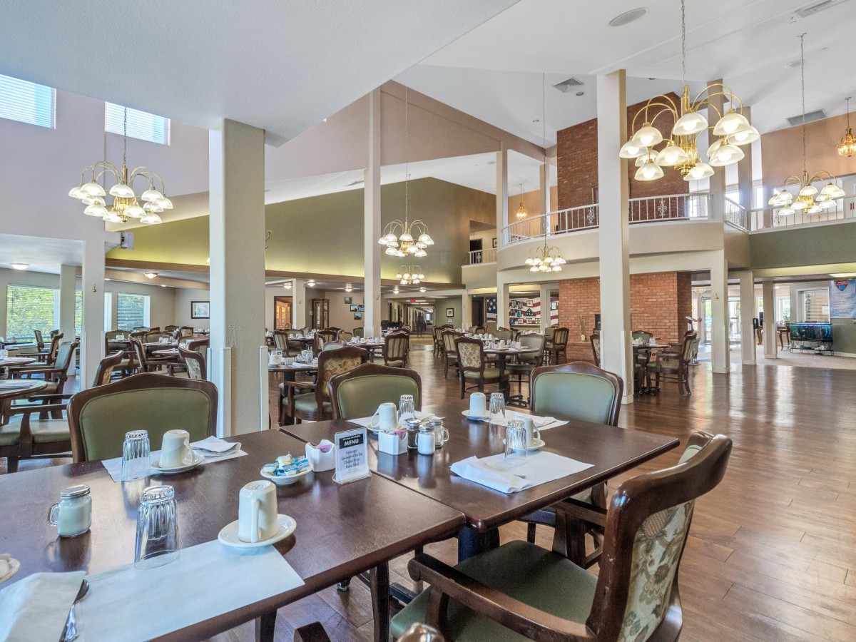 A spacious dining area with neatly arranged tables and elegant chandeliers.
