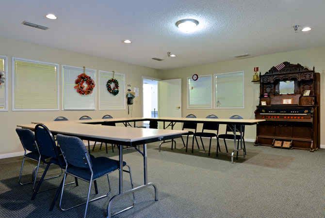 A conference room with tables arranged in a U-shape, surrounded by chairs and decorated with wreaths.