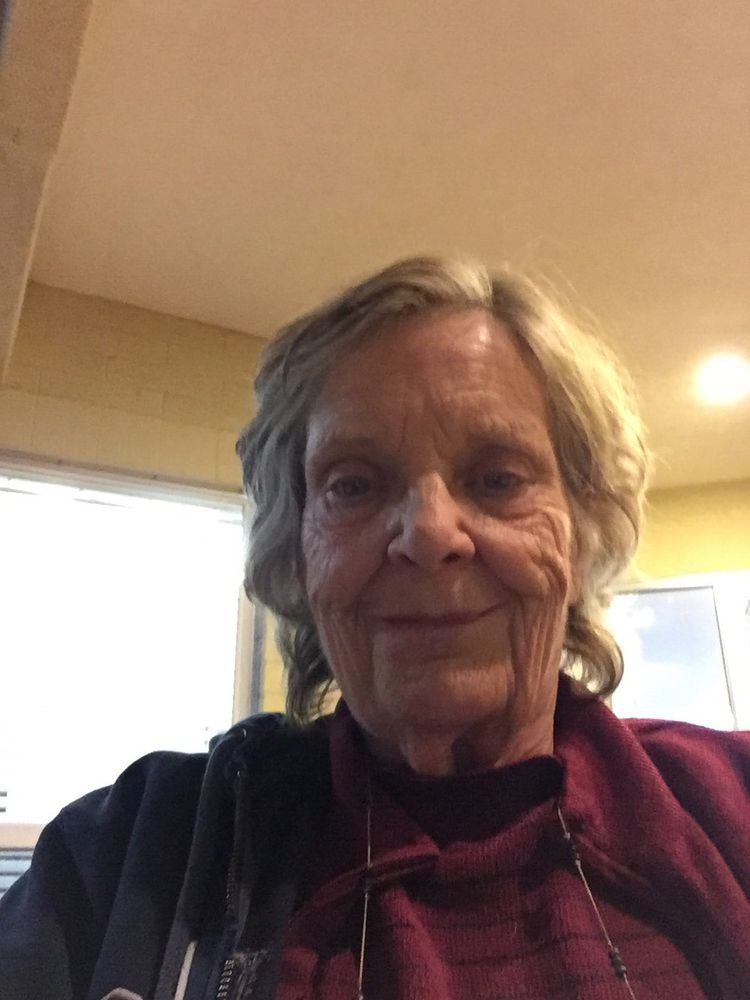 A woman smiling indoors, taking a selfie.