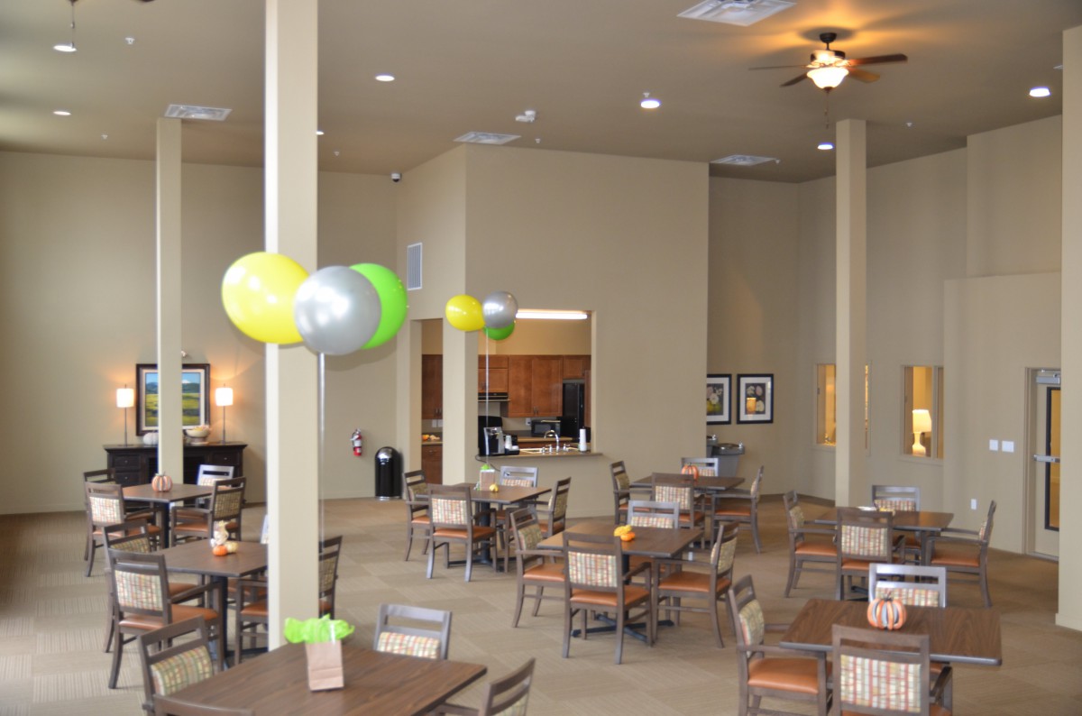 A decorated dining area with tables, chairs, and balloons set up for an event.