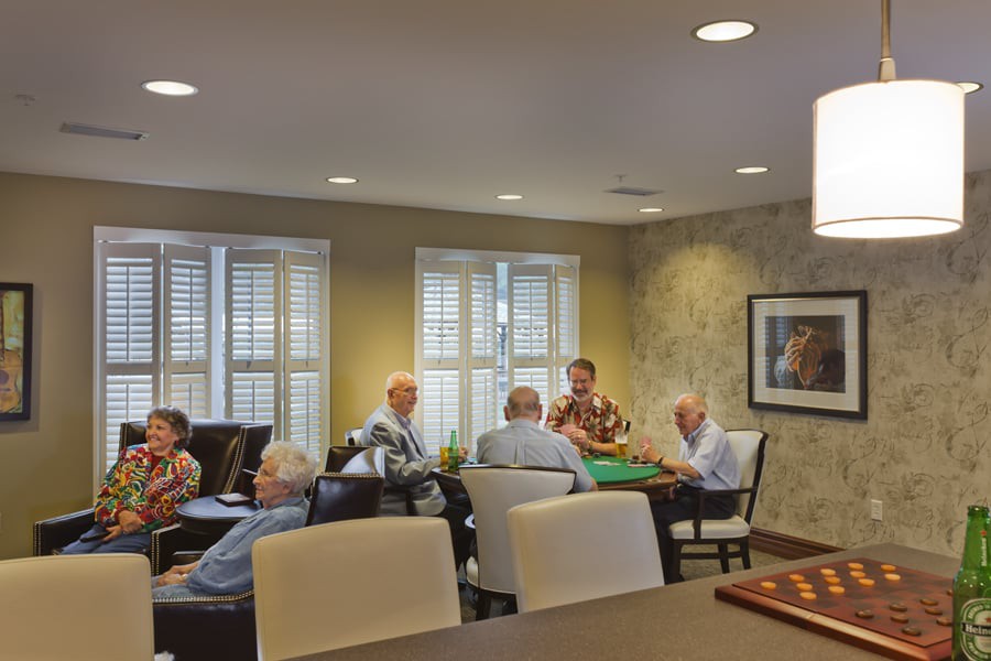 A group of seniors playing cards in a well-lit room, enjoying a social gathering.