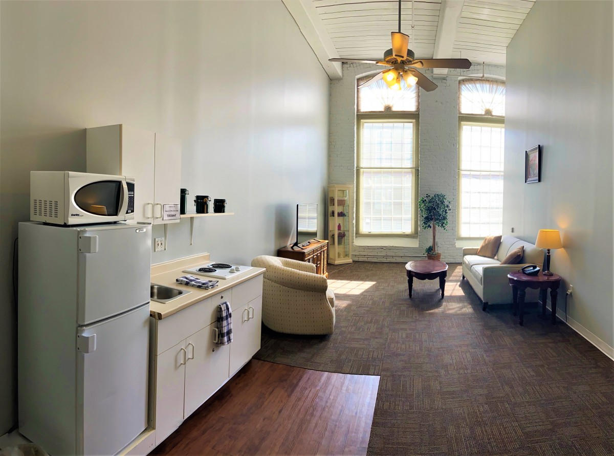 A bright apartment with a living area, kitchenette, and large windows.