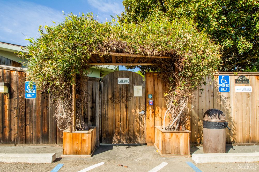 A rustic wooden archway adorned with greenery, marking the entrance to an outdoor area.