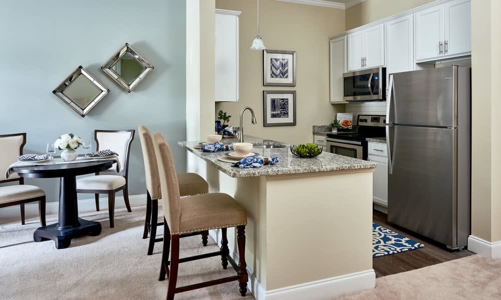 A modern kitchen with bar stools, stainless steel appliances, and stylish decor.