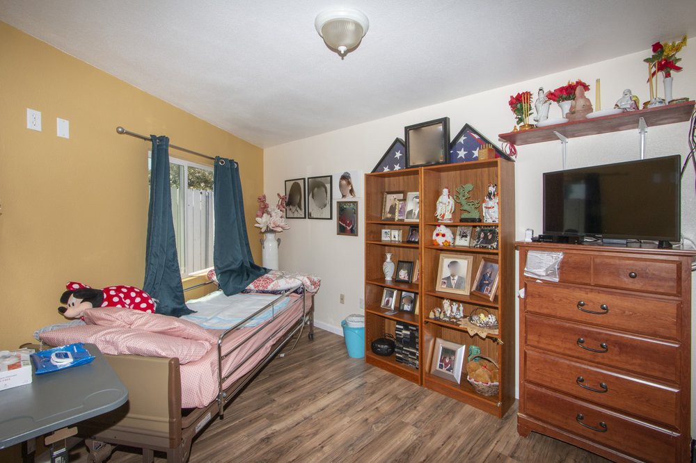 A cozy bedroom with a bed, bookshelf, and television set on a wooden floor.