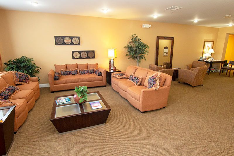 A cozy living room with orange sofas and a coffee table, accented by indoor plants and soft lighting.