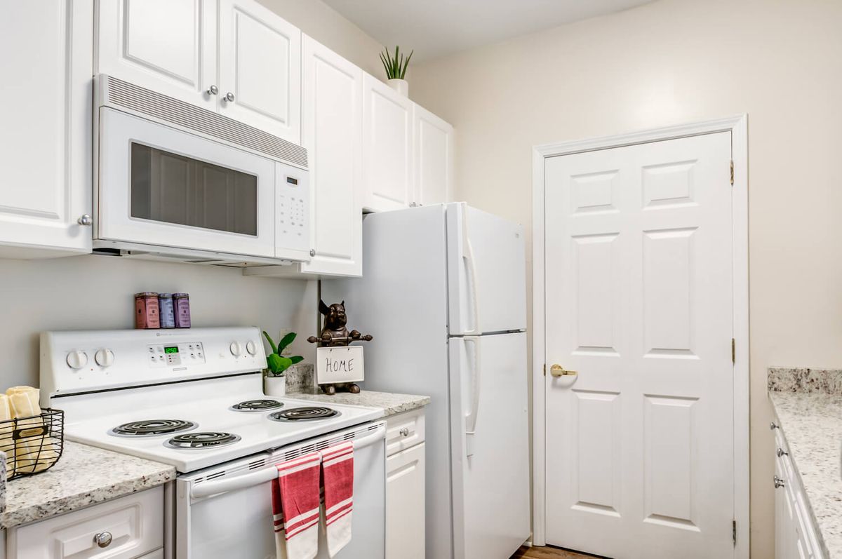 A clean and modern kitchen with white cabinets, a microwave, an oven, and a refrigerator.