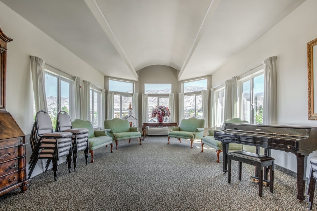 A spacious and bright living room with light green chairs and large windows.