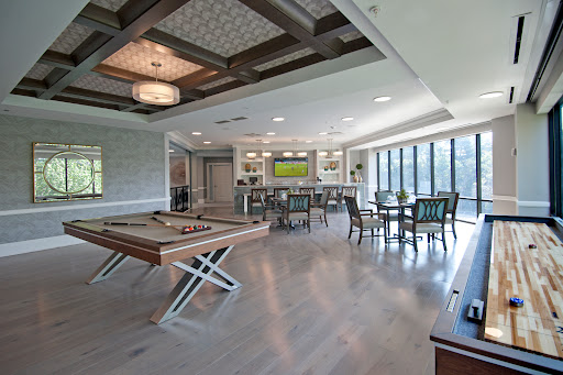 A stylish and spacious modern lounge area featuring a pool table, bar, and ample seating with large windows for natural light.