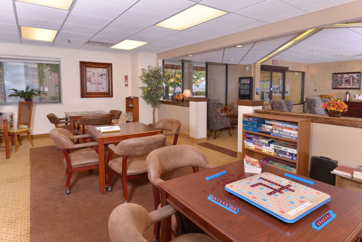 A cozy waiting room with tables, chairs, and games for entertainment.