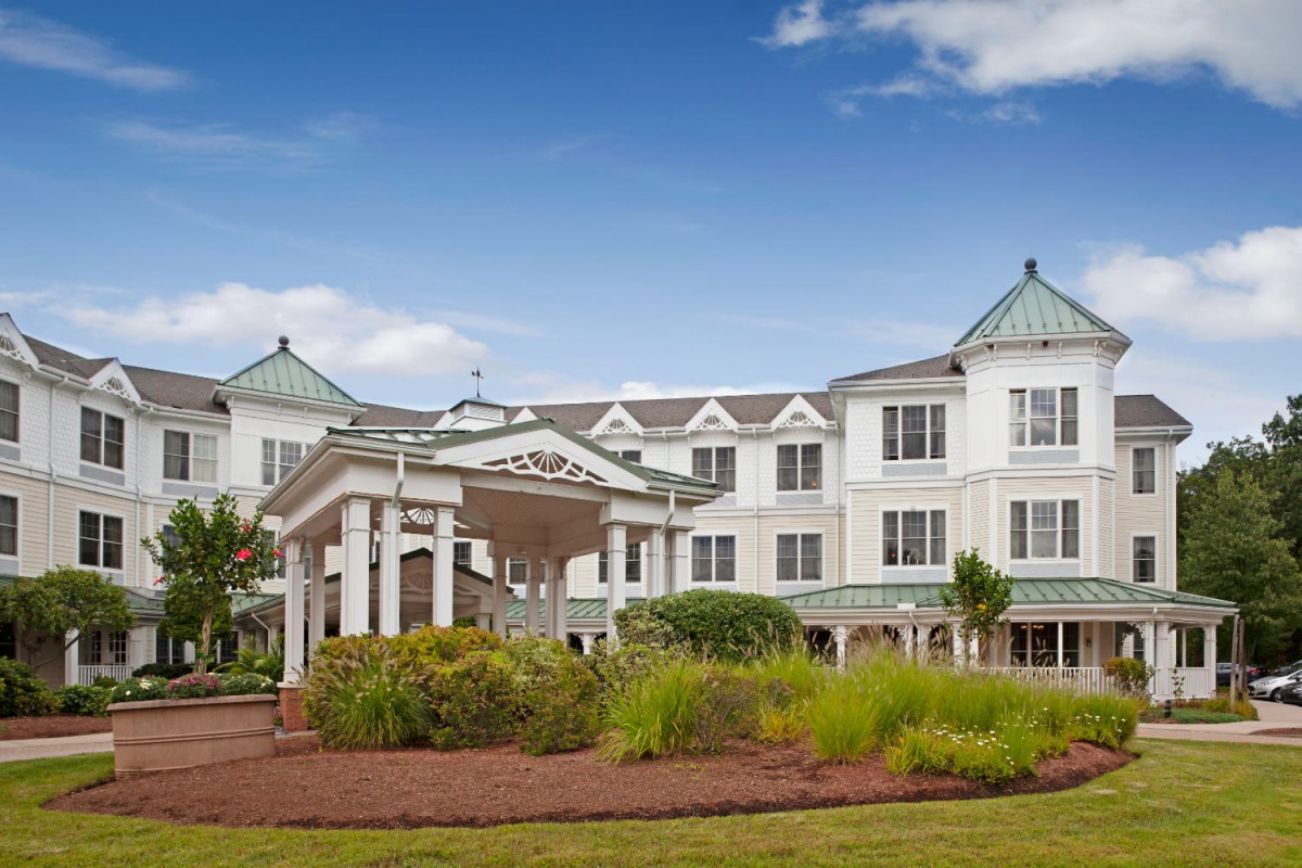 A large, elegant building with landscaped gardens under a clear blue sky.