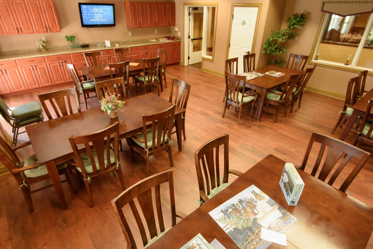 A cozy dining area with wooden tables and chairs, featuring a comfortable indoor atmosphere.