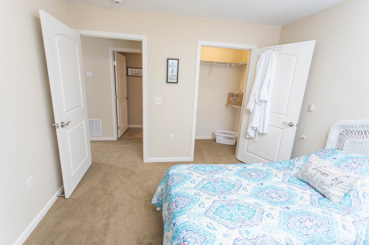 A cozy bedroom with a bed, open closet, and multiple doorways.