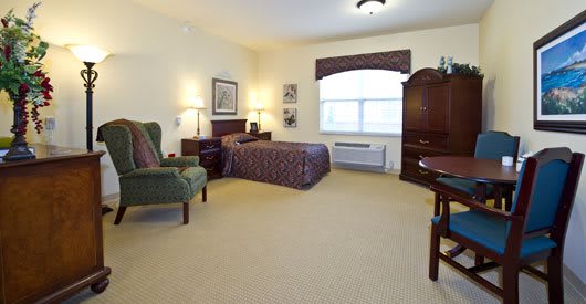 A cozy hotel room with a bed, armchair, and dresser.