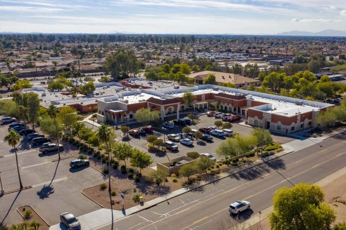 Aerial view of a commercial area with several buildings and a parking lot in a suburban setting.