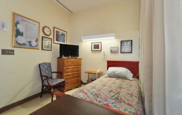 A cozy bedroom with a single bed, television, and various framed artworks on the wall.