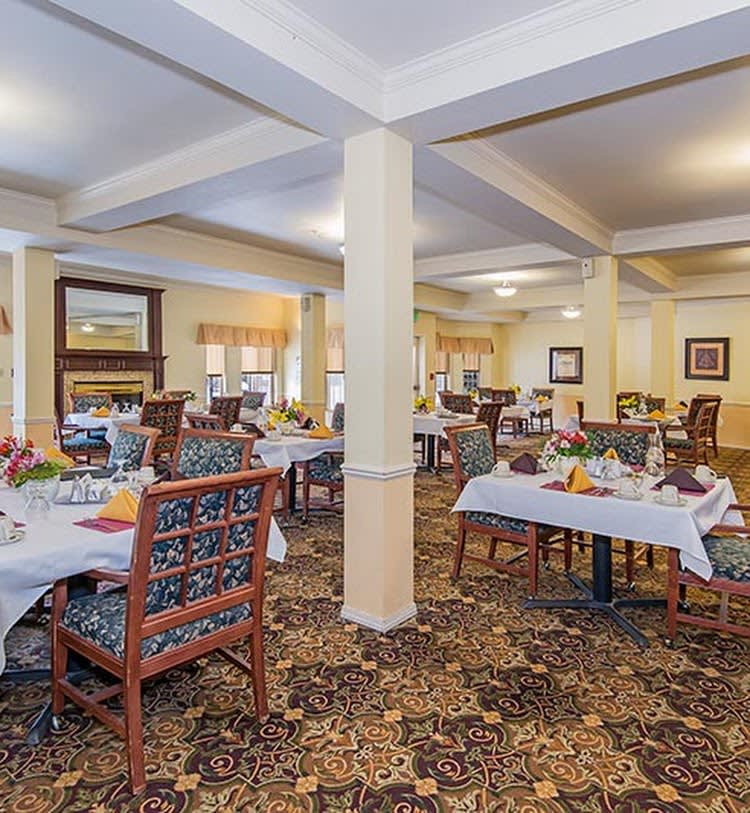 A spacious dining room with neatly arranged tables and chairs, featuring warm lighting and elegant decor.
