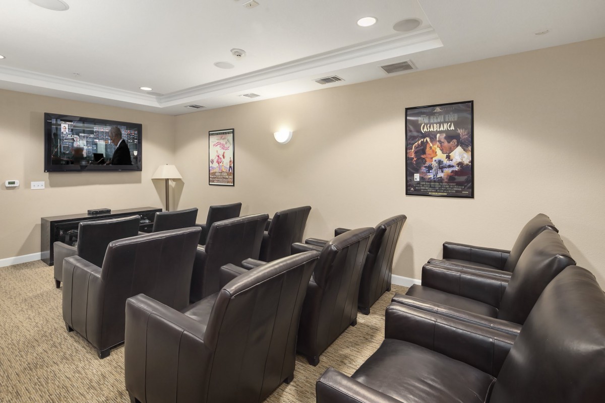 A cozy home theater setup with leather seating and movie posters on the walls.