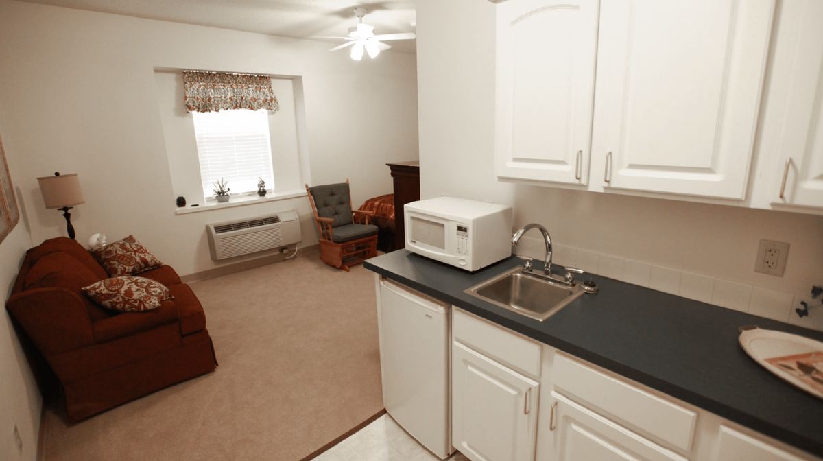A compact studio apartment featuring a kitchenette with a microwave and a cozy living area.