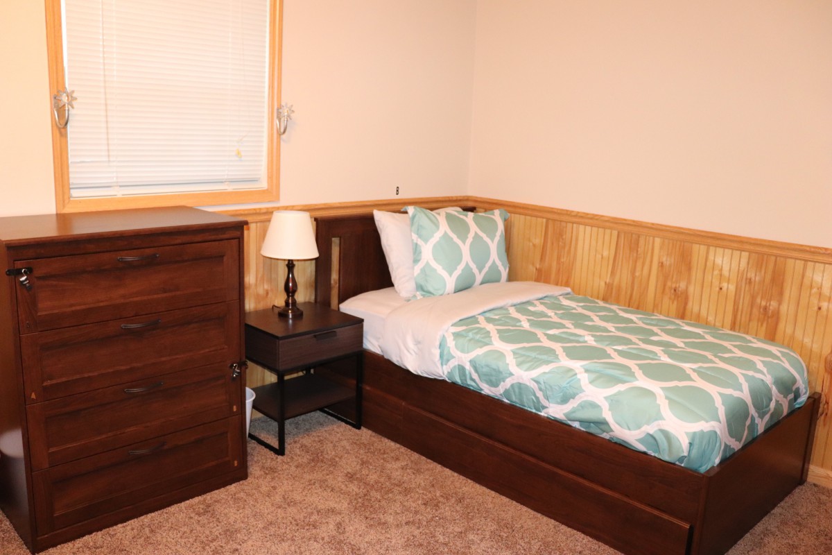 A cozy bedroom with a single bed, nightstand, and dresser.