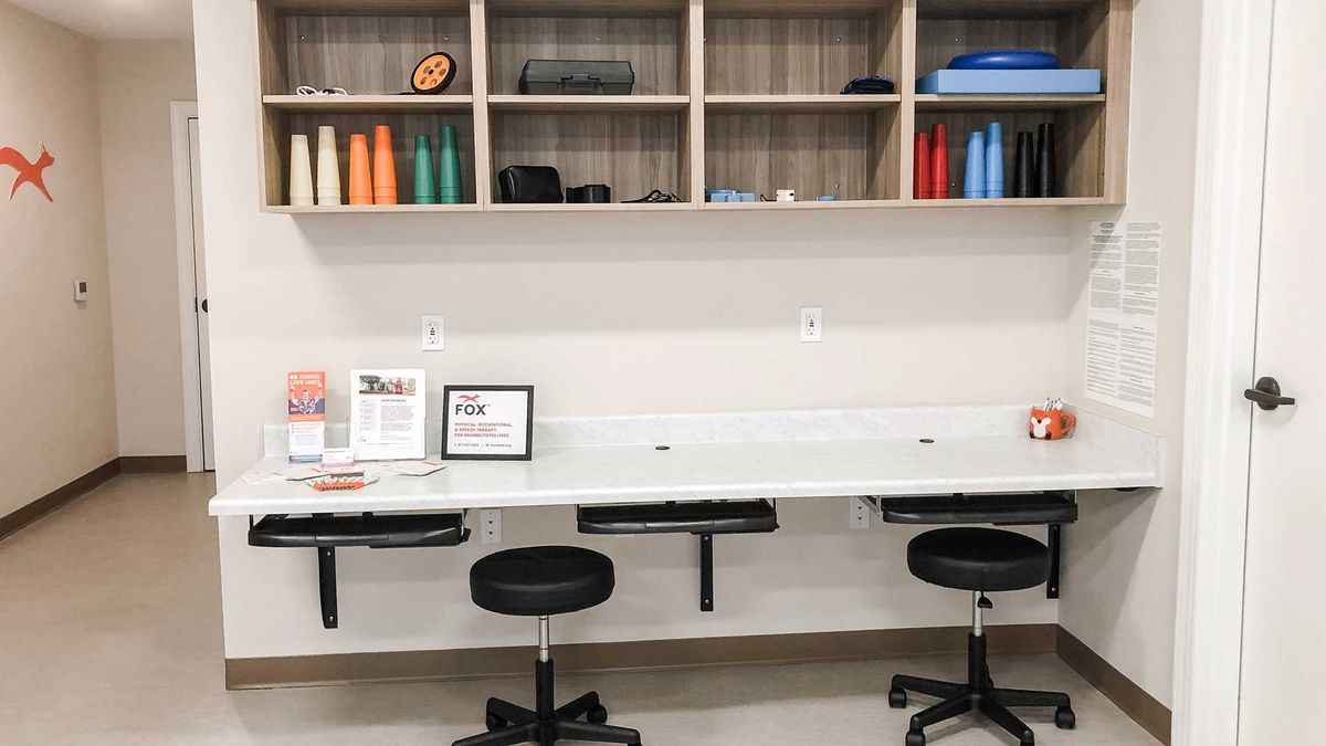 A tidy and organized workspace featuring stools and shelves filled with colorful spools.