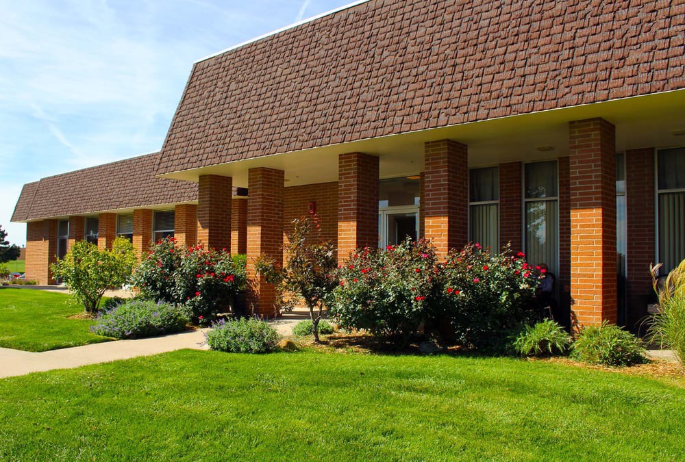 A brick building with a well-maintained garden and lawn.