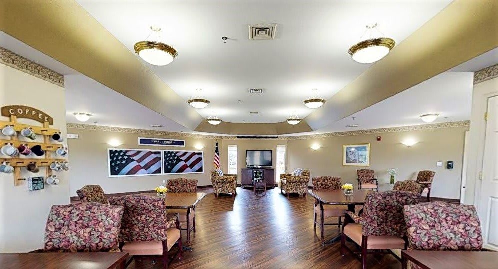 A spacious community room with multiple seating areas, decorated with flags and featuring a television.