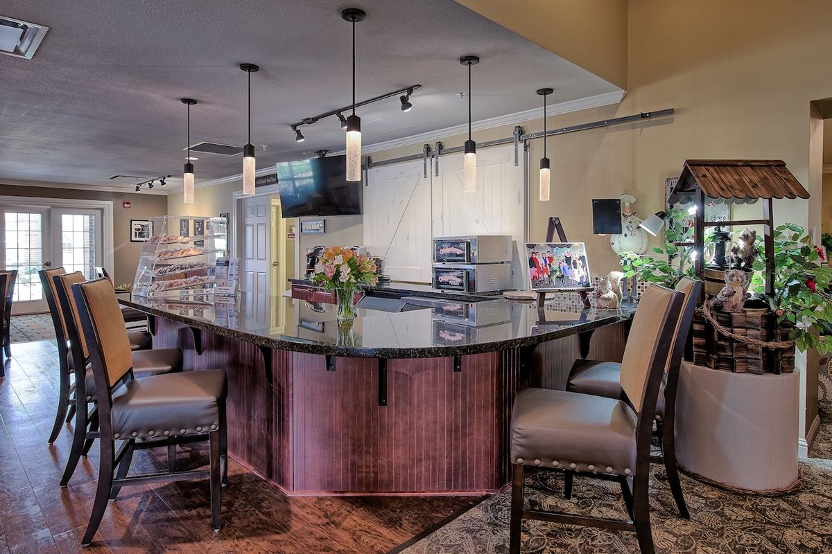 A modern kitchen bar with pendant lighting and high chairs around a central counter.