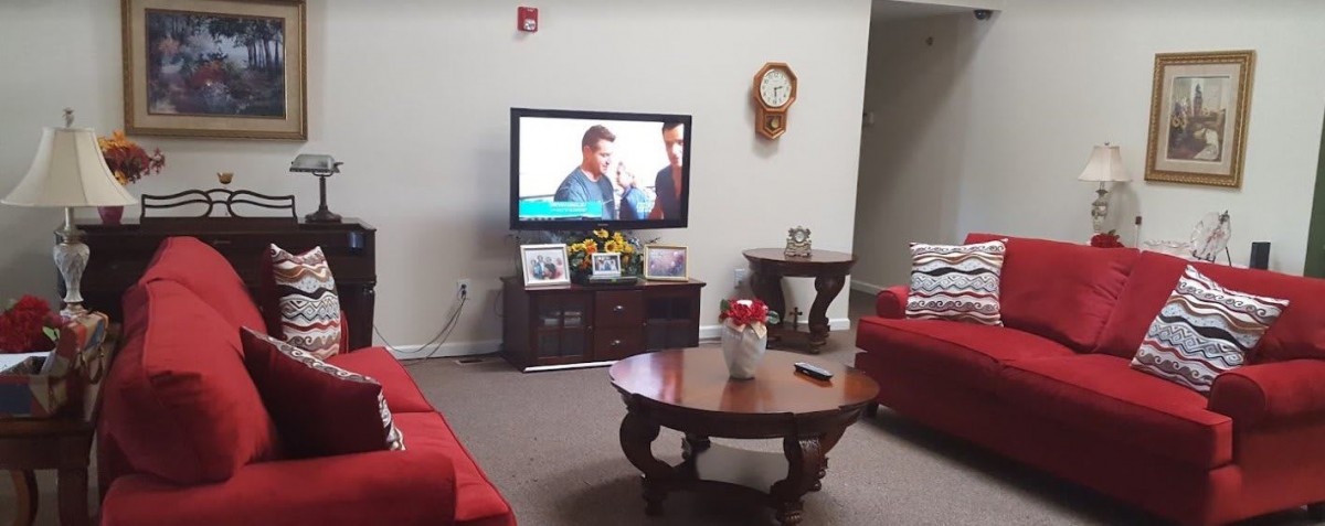 A cozy living room with a television, red sofas, and a wooden coffee table.
