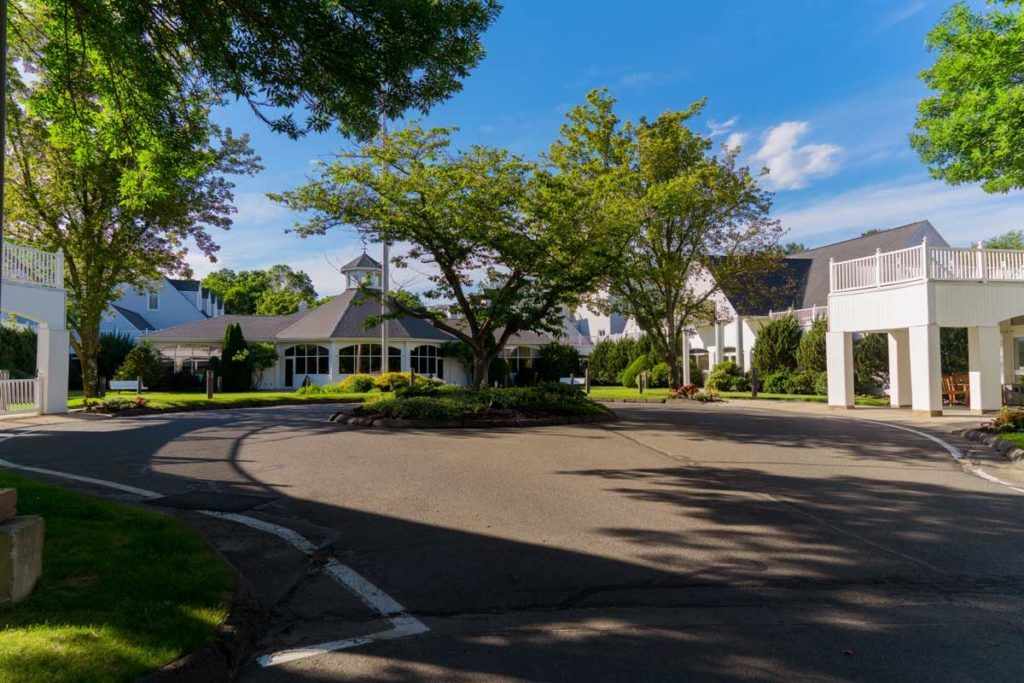 A suburban building surrounded by trees and a driveway on a sunny day.