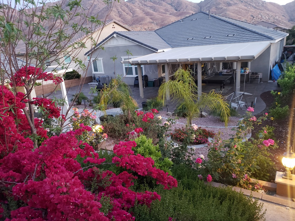 A colorful garden in front of a house with mountains in the background.
