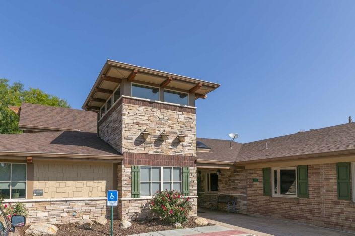A modern residential building with a stone exterior and distinctive tower feature.