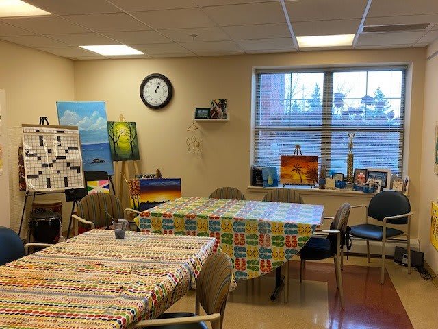 An art room with colorful tablecloths, paintings on easels, and various art supplies.