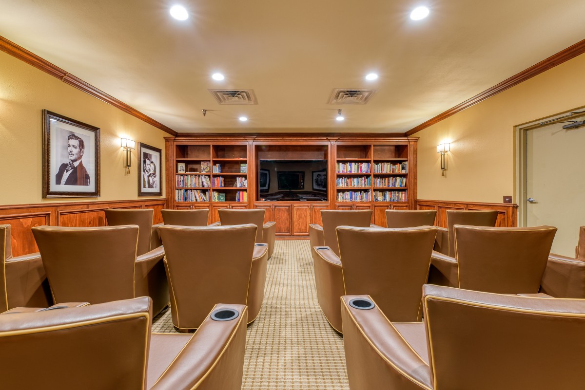 A cozy home theater with comfortable seating and bookshelves in a warmly lit room.