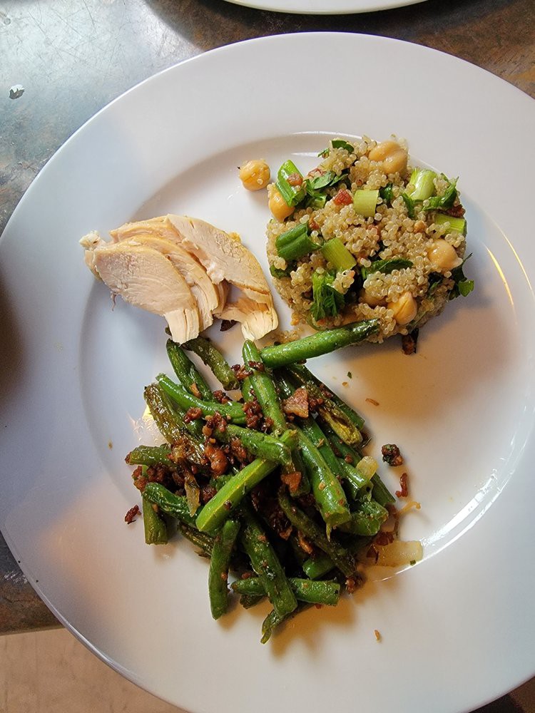 A plate featuring sliced chicken, a quinoa and vegetable mix, and seasoned green beans.