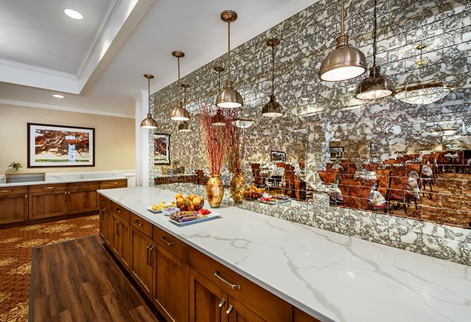 A modern kitchen with a mosaic backsplash, wooden cabinets, and pendant lighting.